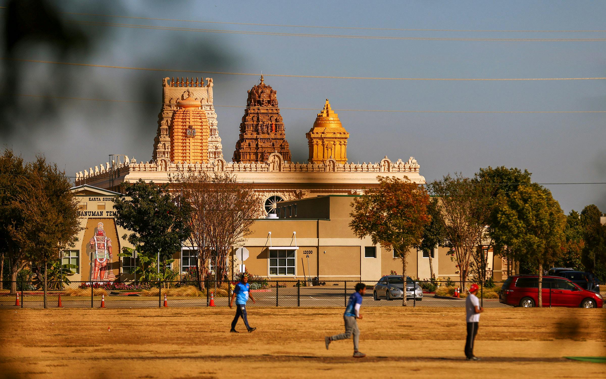 Frisco Hanuman Temple exterior with people walking in foreground, politics