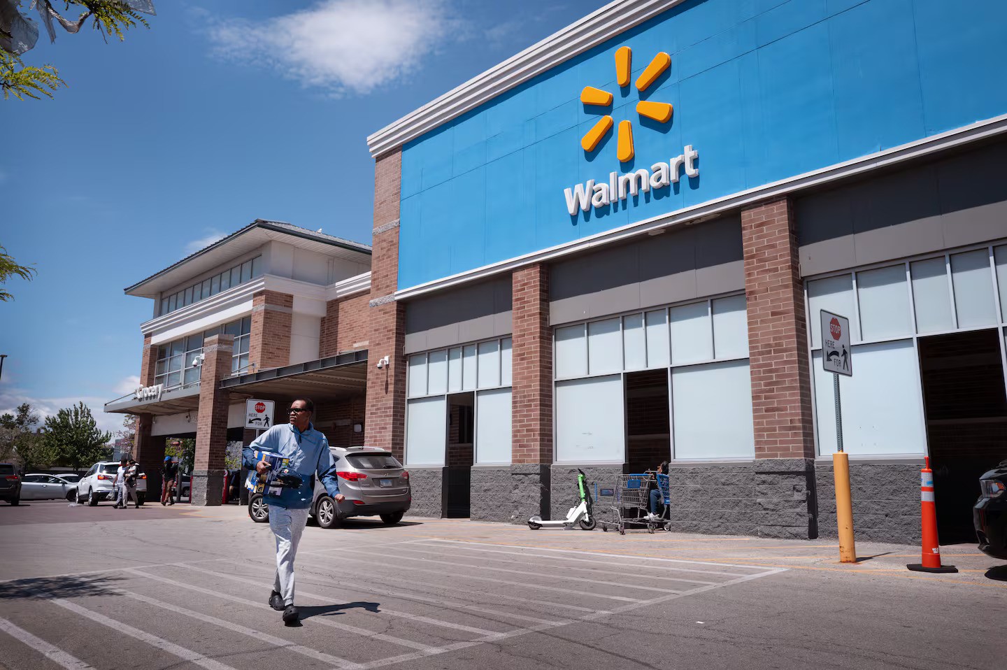 Walmart store exterior, with a man walking in the foreground. Politics.