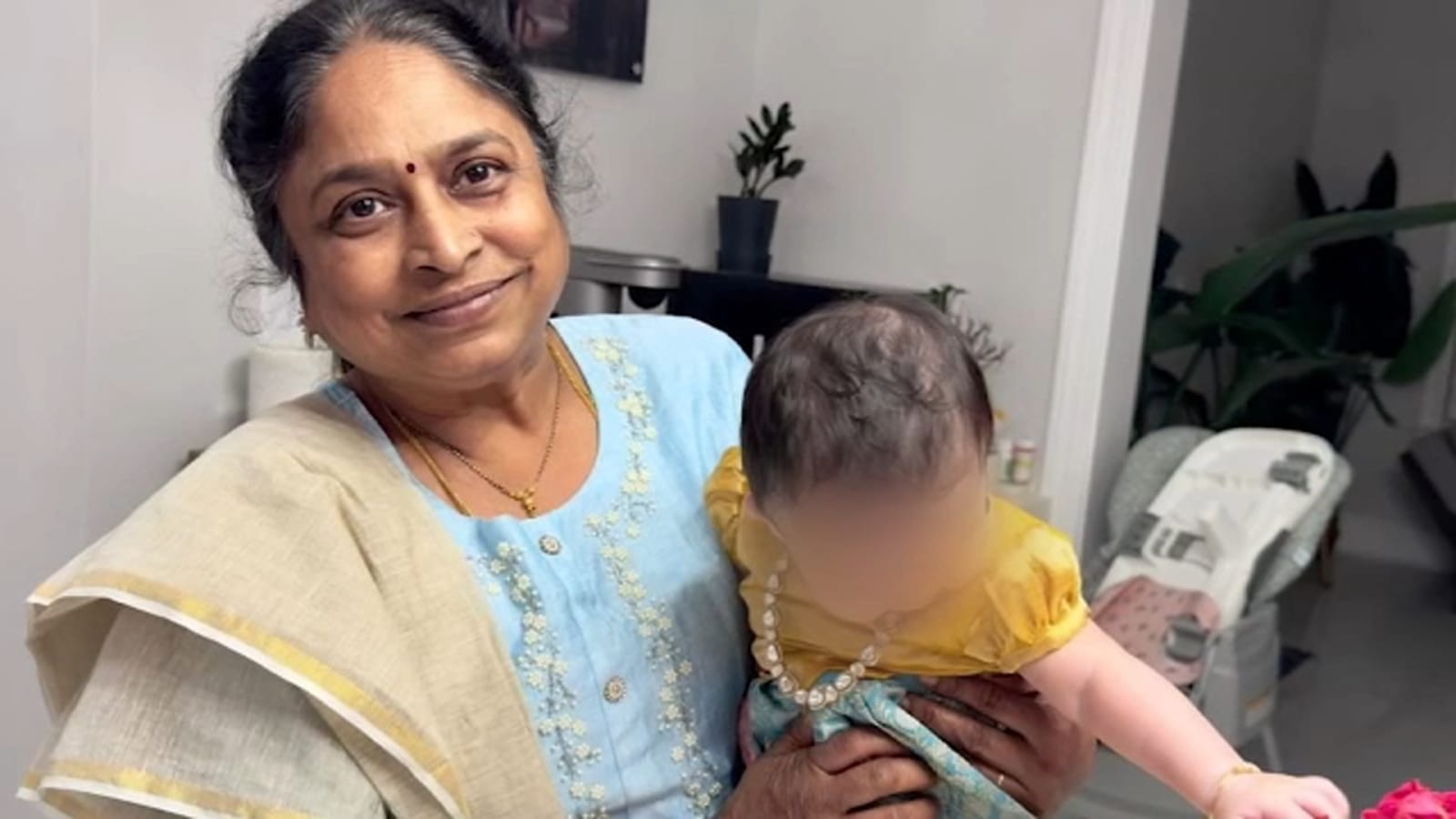 Indian American teacher Venkata holding a baby after ICE case dismissal.