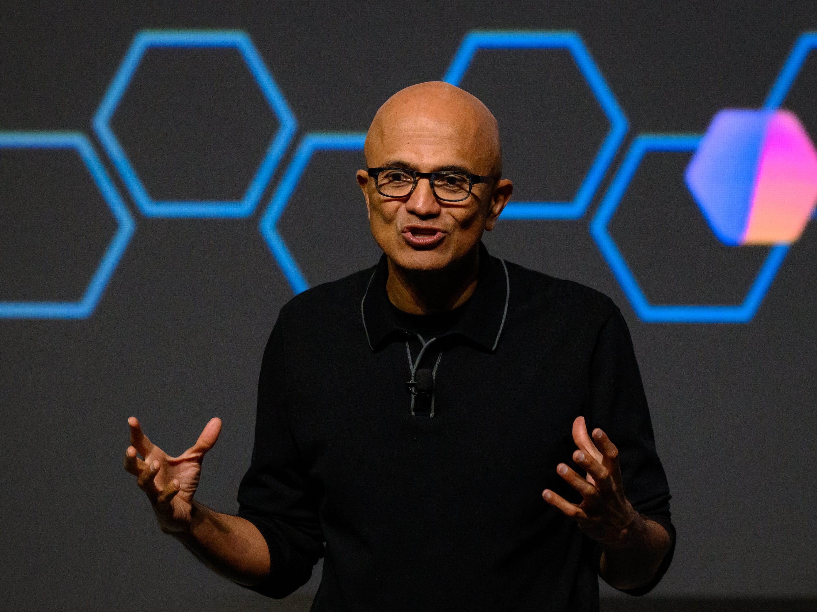 Satya Nadella speaks on stage, discussing tech and AI.