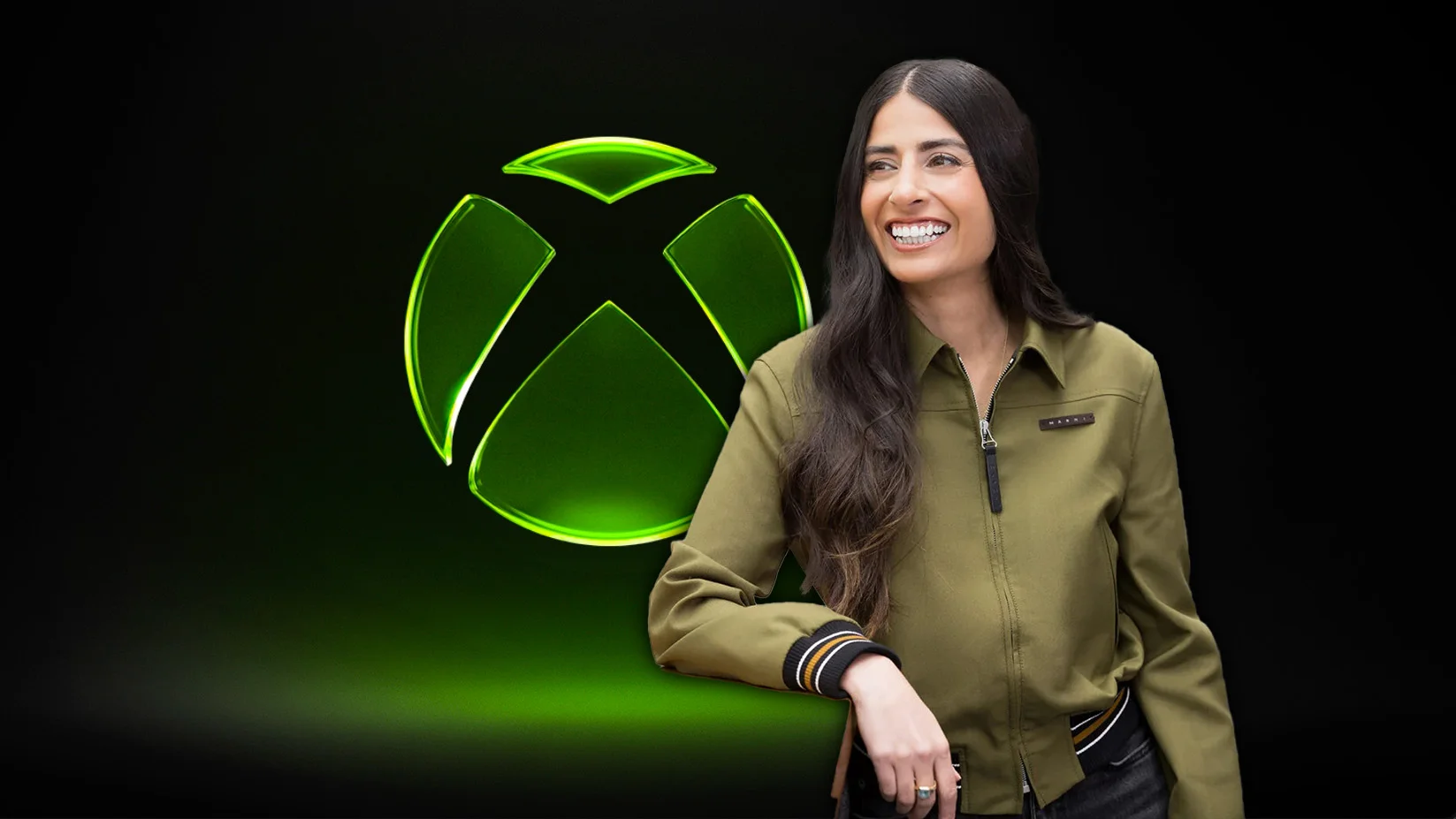 Xbox CEO Asha Sharma smiles next to the Xbox logo, discussing business.