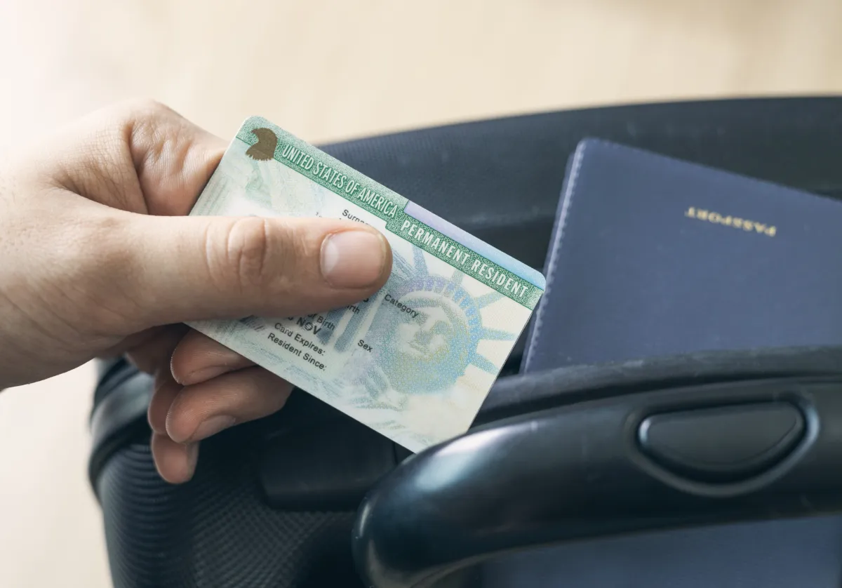 Green card and passport in a suitcase, relevant for visa & immigration.