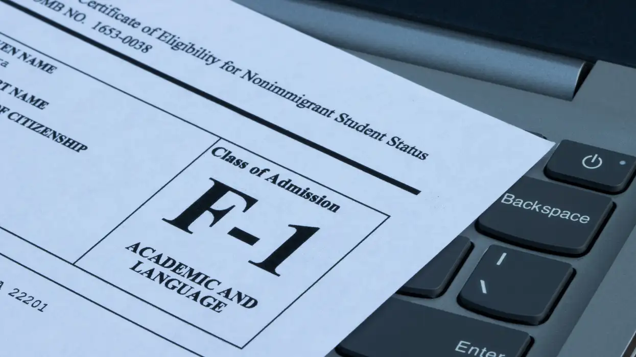 F-1 Student Visa document on a laptop keyboard, related to immigration changes.