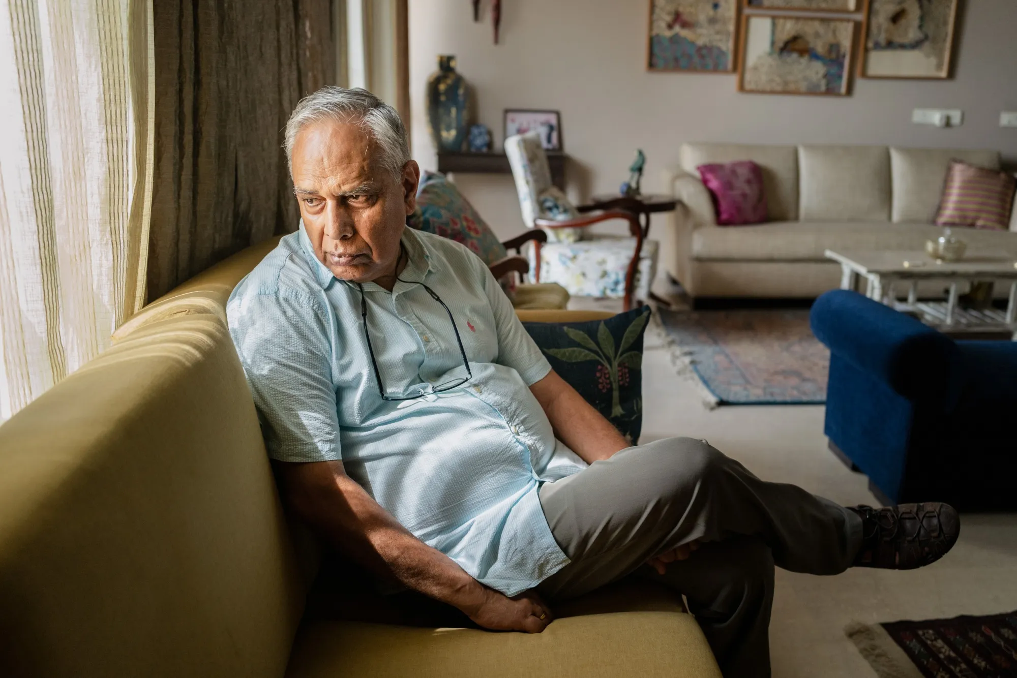 Indian American professor looking concerned in a living room
