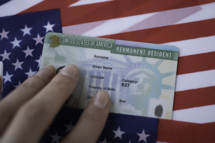 US Permanent Resident Green Card on American flag, relevant to visa and immigration costs.